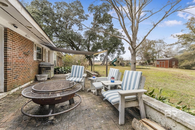 view of patio / terrace featuring area for grilling, a storage unit, a playground, and an outdoor fire pit