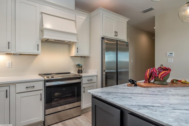 kitchen featuring pendant lighting, white cabinets, stainless steel appliances, premium range hood, and light wood-type flooring