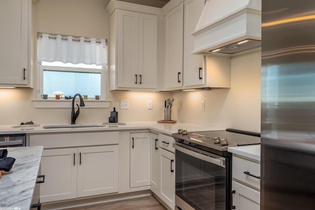 kitchen with stainless steel appliances, light hardwood / wood-style floors, custom exhaust hood, sink, and white cabinets