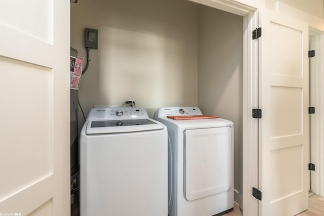 laundry room with washing machine and dryer and light wood-type flooring