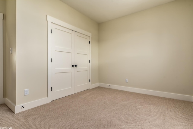 unfurnished bedroom featuring a closet and light colored carpet