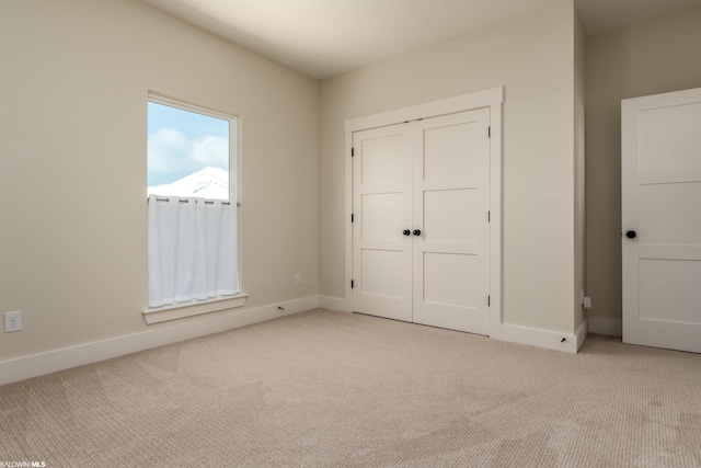 unfurnished bedroom with a closet and light colored carpet