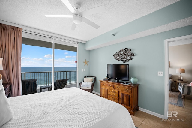 bedroom featuring access to outside, light tile patterned flooring, a textured ceiling, a wall of windows, and ceiling fan