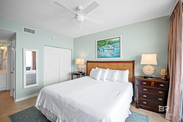 bedroom featuring a closet, a textured ceiling, a ceiling fan, light tile patterned flooring, and connected bathroom