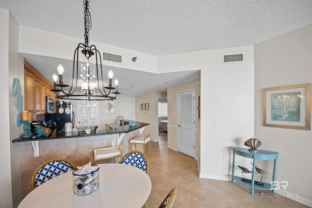 dining space featuring a textured ceiling, a chandelier, baseboards, and light tile patterned floors