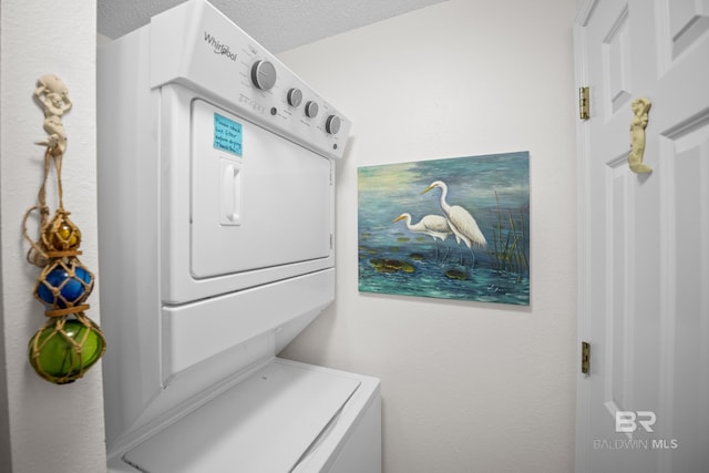washroom with estacked washer and dryer and a textured ceiling