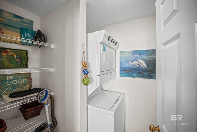 laundry room featuring stacked washer / dryer and a textured ceiling