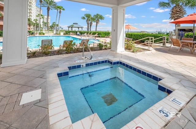 community pool with a community hot tub and a patio area