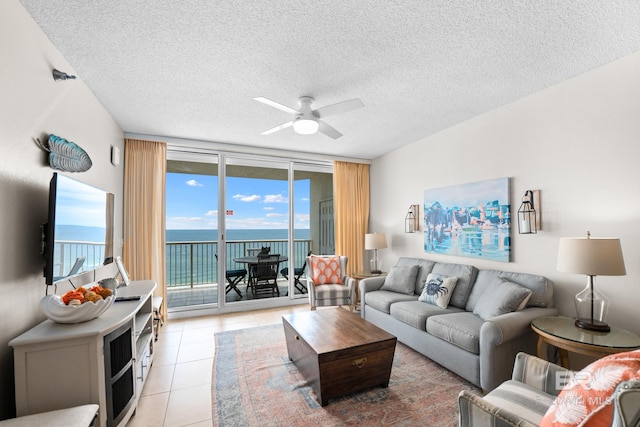 living area featuring a ceiling fan, light tile patterned flooring, and a textured ceiling
