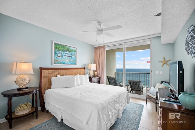 bedroom featuring access to exterior, a textured ceiling, light tile patterned floors, a ceiling fan, and a wall of windows