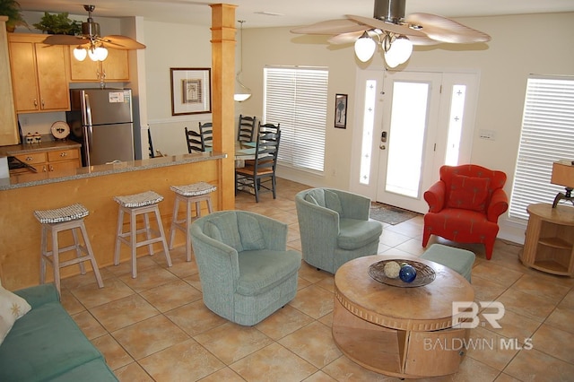 living room with light tile patterned floors, decorative columns, and ceiling fan