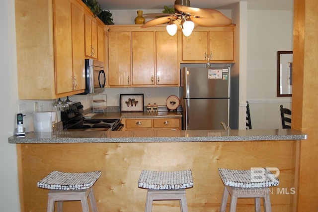 kitchen with stainless steel appliances, a breakfast bar area, ceiling fan, and kitchen peninsula