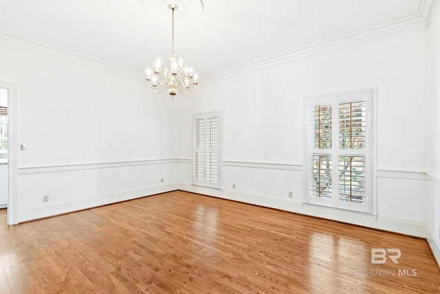 empty room featuring hardwood / wood-style floors, a notable chandelier, and ornamental molding