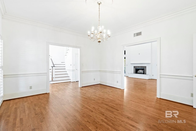 unfurnished dining area featuring hardwood / wood-style flooring, a notable chandelier, and crown molding