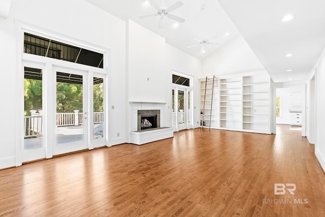 unfurnished living room featuring ceiling fan, light wood-type flooring, and high vaulted ceiling