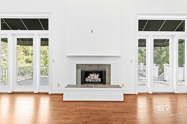 unfurnished living room with hardwood / wood-style flooring and a tiled fireplace