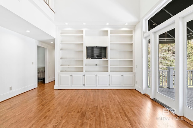 unfurnished living room with built in features and light hardwood / wood-style floors