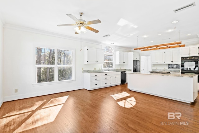 kitchen featuring ornamental molding, black appliances, white cabinets, light hardwood / wood-style floors, and a kitchen island