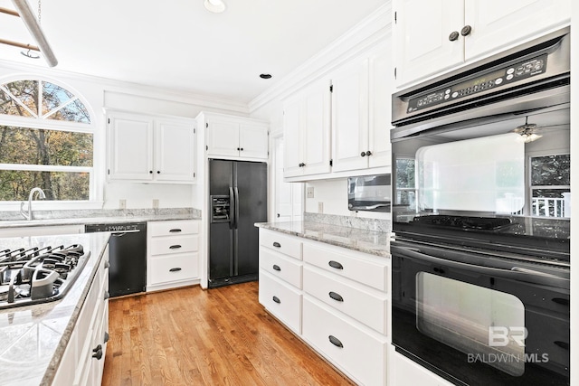 kitchen featuring sink, light wood-type flooring, white cabinets, black appliances, and ornamental molding