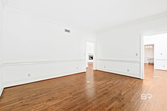 spare room featuring crown molding, hardwood / wood-style floors, and an inviting chandelier