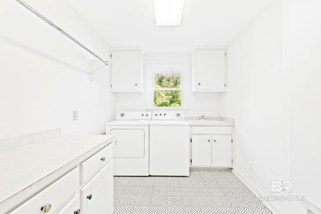 clothes washing area with washer and clothes dryer, cabinets, and sink