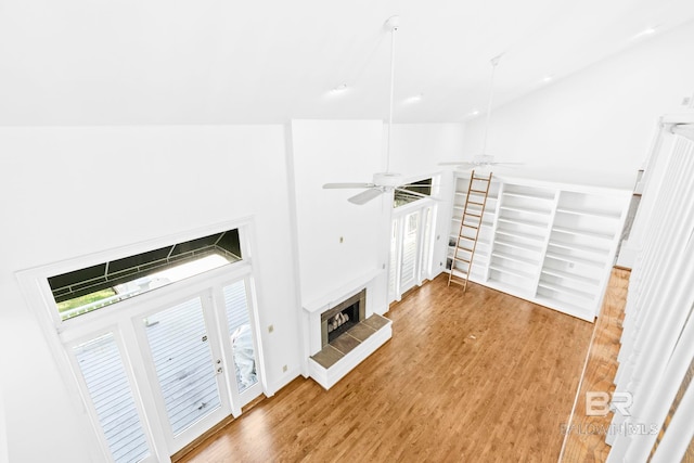 unfurnished living room with a fireplace, wood-type flooring, french doors, and ceiling fan