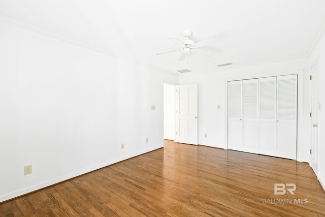 unfurnished bedroom with ceiling fan, a closet, ornamental molding, and hardwood / wood-style flooring