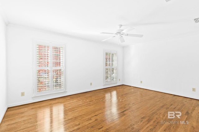 empty room with light hardwood / wood-style flooring, a wealth of natural light, ornamental molding, and ceiling fan