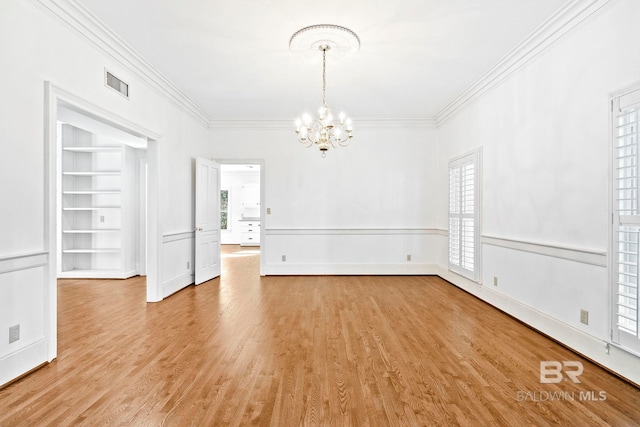 interior space featuring crown molding, built in features, a healthy amount of sunlight, and an inviting chandelier