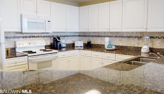 kitchen featuring white appliances, white cabinetry, and dark stone counters