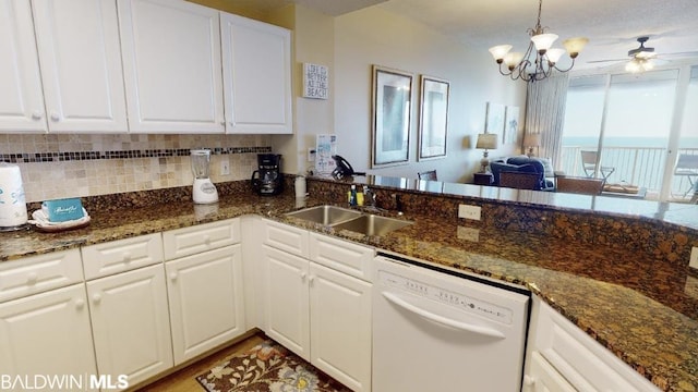 kitchen with white dishwasher, ceiling fan with notable chandelier, sink, and white cabinetry