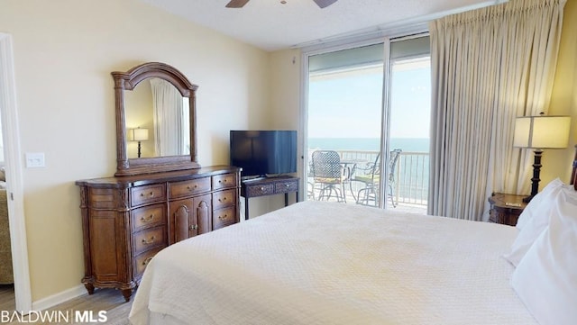 bedroom with ceiling fan, access to exterior, and a water view