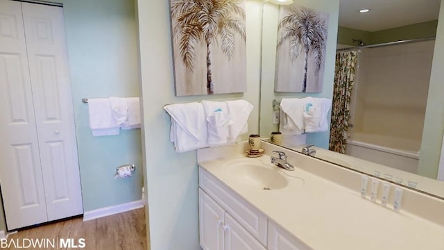 bathroom featuring hardwood / wood-style flooring, oversized vanity, and shower / tub combo with curtain