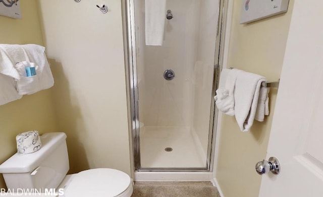 bathroom featuring a shower with door and toilet