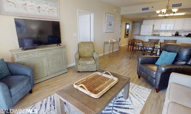 living room with an inviting chandelier and light hardwood / wood-style flooring