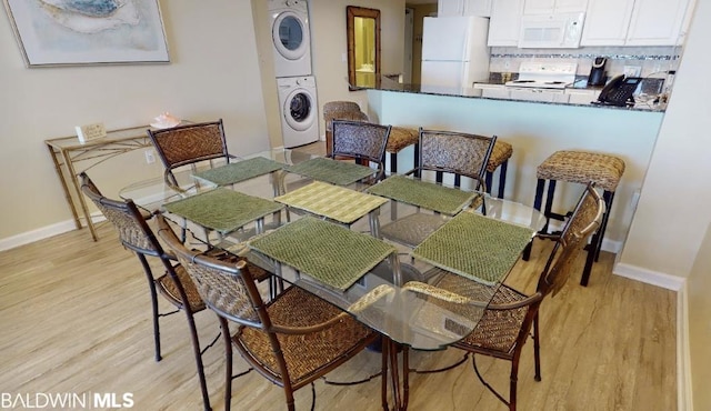 dining space featuring stacked washer and dryer and light hardwood / wood-style floors