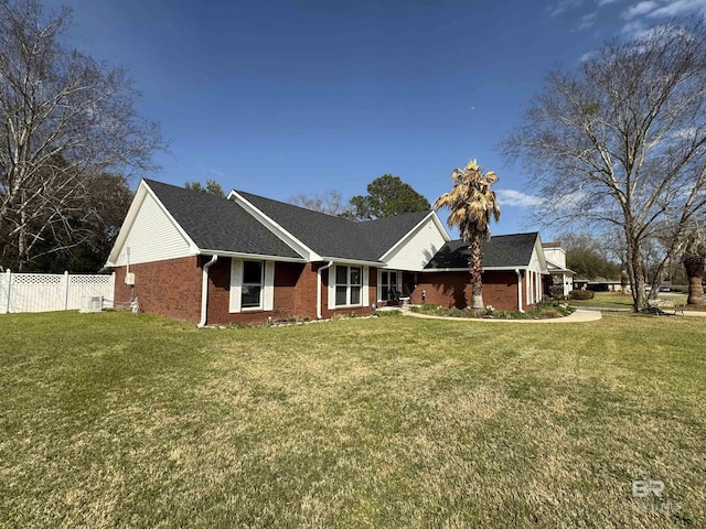 single story home with a front lawn, fence, and brick siding