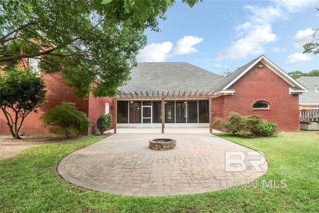 back of house featuring a yard, a patio, a sunroom, and an outdoor fire pit