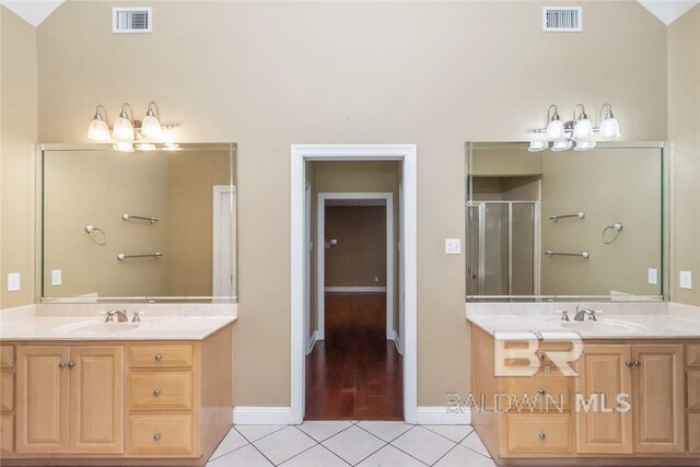 bathroom featuring vanity, lofted ceiling, an enclosed shower, and tile patterned floors