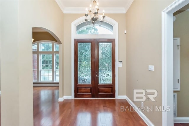 entrance foyer with crown molding, french doors, dark hardwood / wood-style flooring, and an inviting chandelier