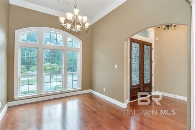 entrance foyer with lofted ceiling, hardwood / wood-style floors, an inviting chandelier, and crown molding