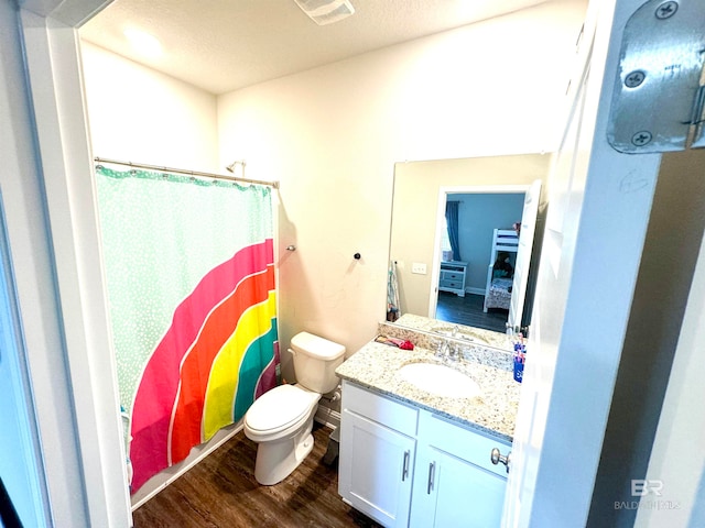 bathroom featuring hardwood / wood-style floors, a textured ceiling, walk in shower, toilet, and vanity