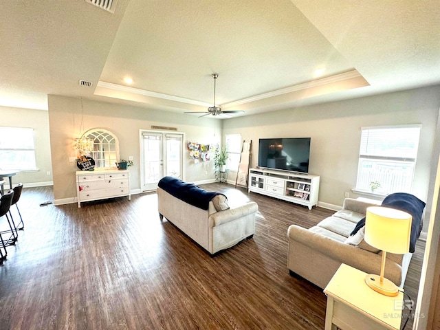 living room featuring dark hardwood / wood-style floors, a textured ceiling, a tray ceiling, and ceiling fan