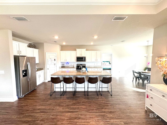 kitchen with appliances with stainless steel finishes, dark hardwood / wood-style floors, white cabinetry, and an island with sink