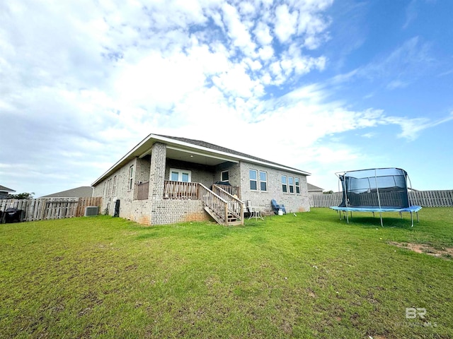 back of house featuring a yard, cooling unit, and a trampoline