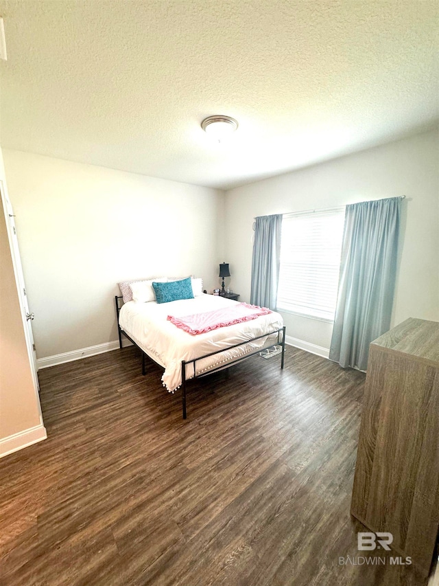 bedroom with a textured ceiling and dark hardwood / wood-style flooring