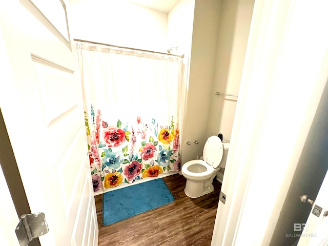 bathroom with a shower with shower curtain, hardwood / wood-style flooring, and toilet