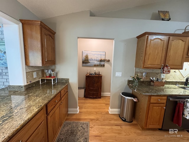 1052 Orlando Dr, Foley, AL 36535 - kitchen with dishwasher, vaulted ceiling, light wood-type flooring, decorative backsplash, and dark stone countertops