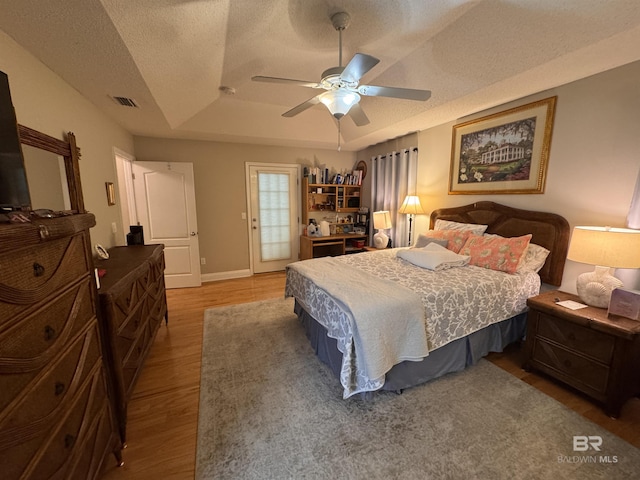 1052 Orlando Dr, Foley, AL 36535 - bedroom featuring a raised ceiling, wood finished floors, a textured ceiling, baseboards, and ceiling fan