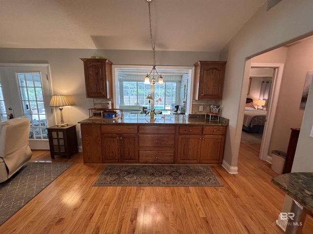 1052 Orlando Dr, Foley, AL 36535 - kitchen with light wood-style floors, brown cabinets, healthy amount of natural light, decorative light fixtures, and lofted ceiling